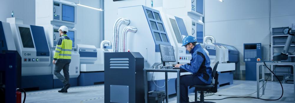 Workers in a modern factory with a Bodet digital clock, illustrating a lockdown and emergency alert system.