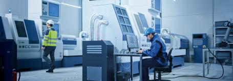 Workers in a modern factory with a Bodet digital clock, illustrating a lockdown and emergency alert system.